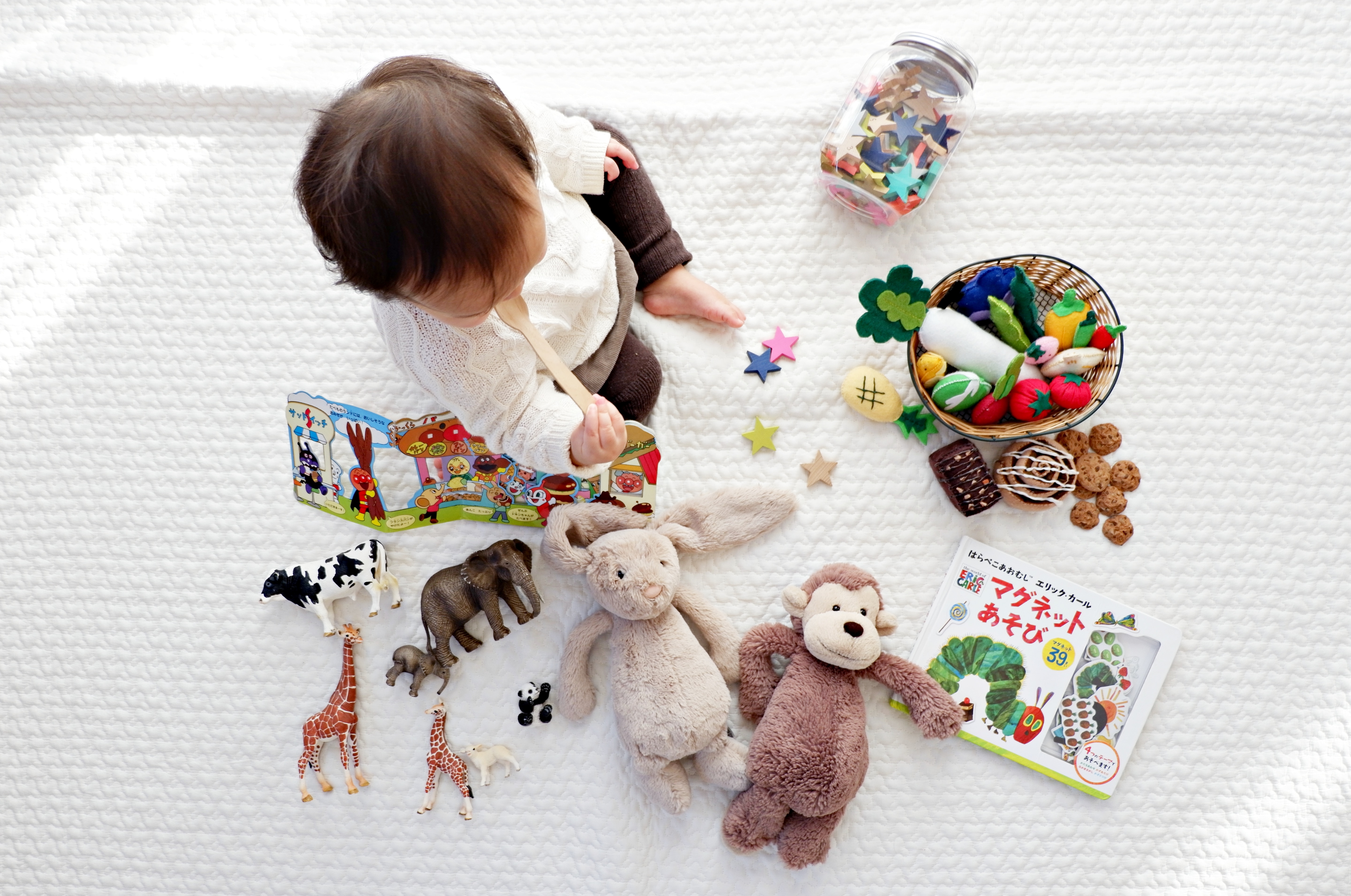 toddler surrounded by toys and stuffed animals